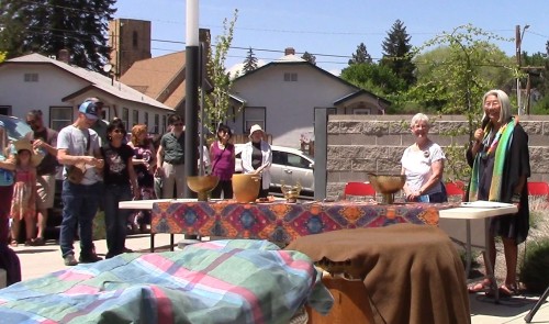 Estelle and Gayle stand behind a table and address the crowd outside